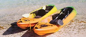 A picture of two canoes with paddles on a beach