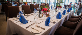 A picture of a dining table, utensils, wine in an event space