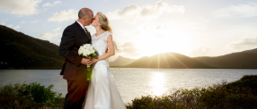 A picture of a bride and groom kissing with an island in the background