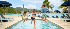 three kids jumping into beachside pool at Scrub Island Resort