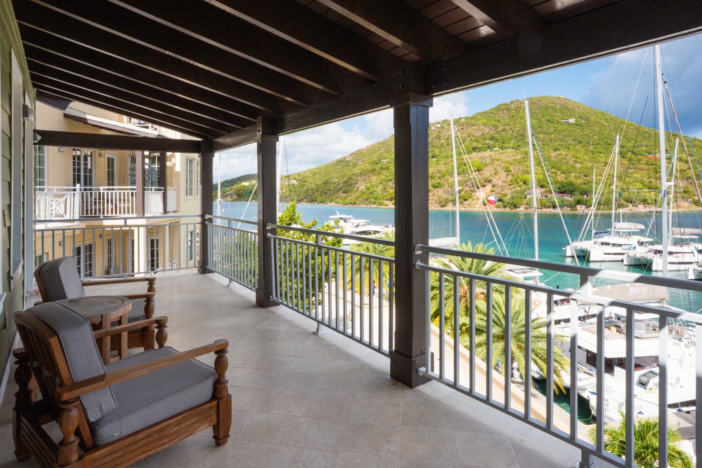 a covered balcony of a suite overlooking a marina on a private Caribbean island